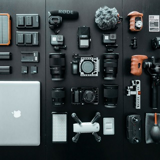 divers éléments d'appareils photos posés sur un fond noir et un mac